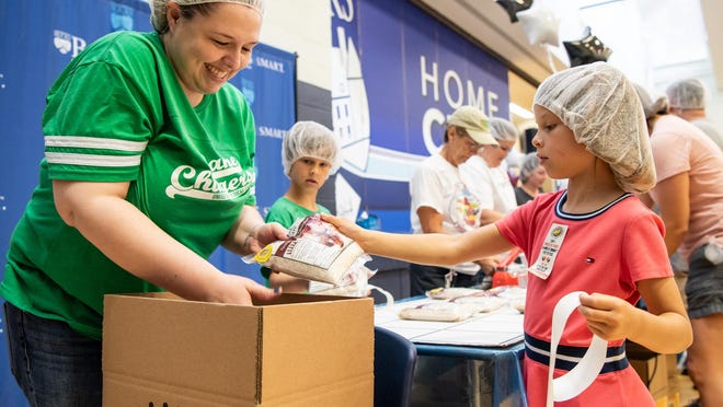 File - Faith Parkinson, left, director of finance at the United Way of Bucks County, and Charlotte Strouse, 7, of Middletown, stickers and packs meals with her brother, Walter Strouse, 8, during the 2019 Bucks Knocks Out Hunger event. The popular food-packing event returns June 17.