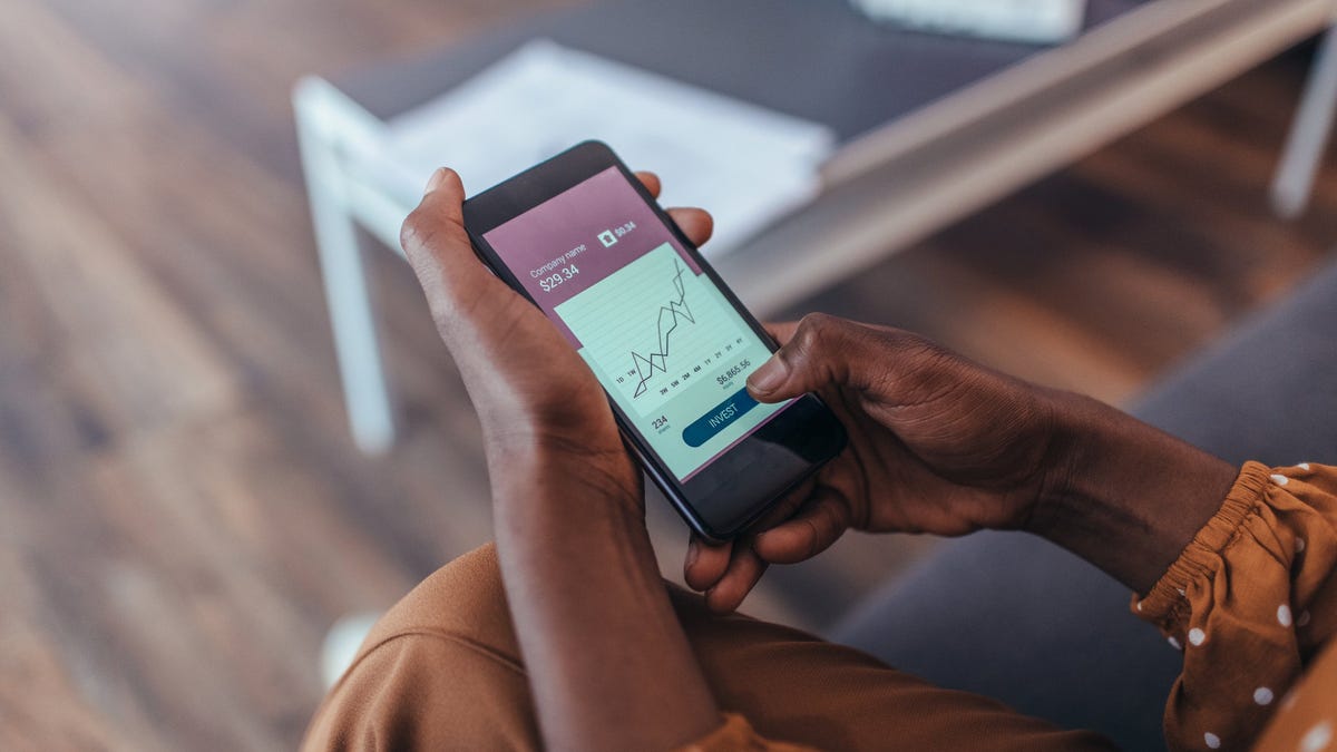 Person holding a phone with stock market chart on it