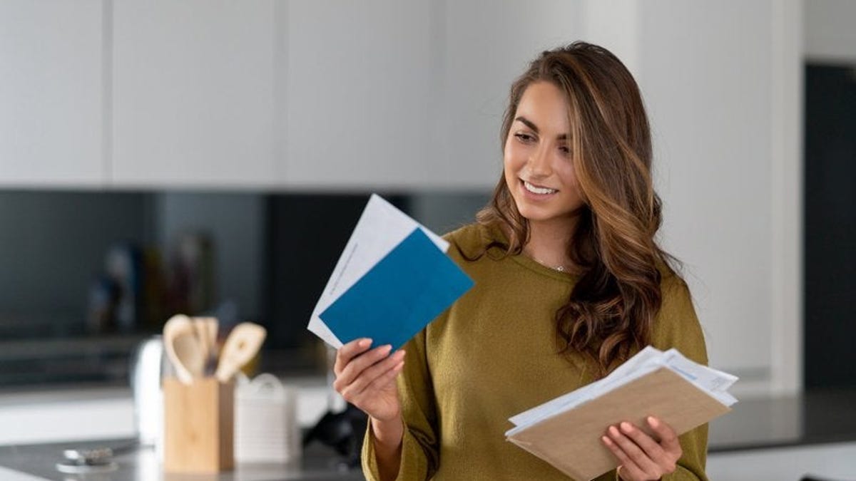 A woman holding her mail while standing in her kitchen.