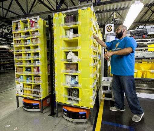 Amazon worker picking items in a fulfillment center.