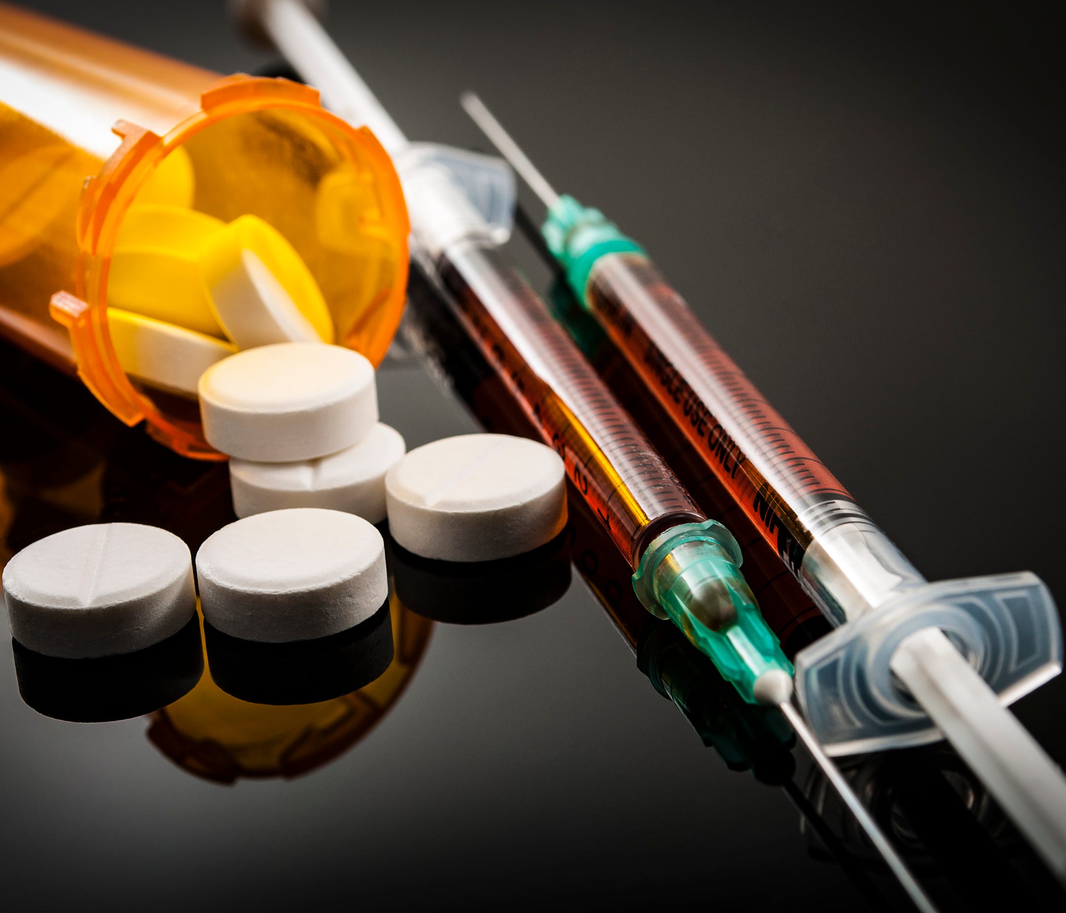 Opioid epidemic, drug abuse concept with closeup on two heroin syringes or other narcotics surrounded by scattered prescription opioids. Oxycodone is the generic name for a range of opioid painkillers