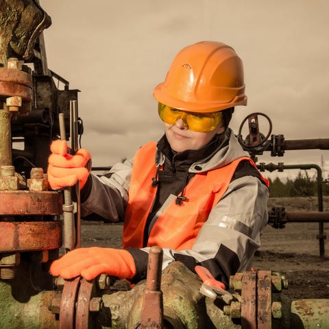 Person wearing hard hat working on oil well equipm