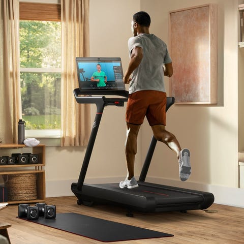 A person running on a Peloton treadmill watching a