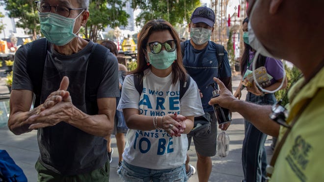 A doorman distributes hand sanitizing liquid for visitors at a luxury mall in Bangkok, Thailand, Tuesday, Jan. 28, 2020. Panic and pollution drive the market for protective face masks, so business is booming in Asia, where fear of the coronavirus from China is straining supplies and helping make mask-wearing the new normal. (AP Photo/Gemunu Amarasinghe)