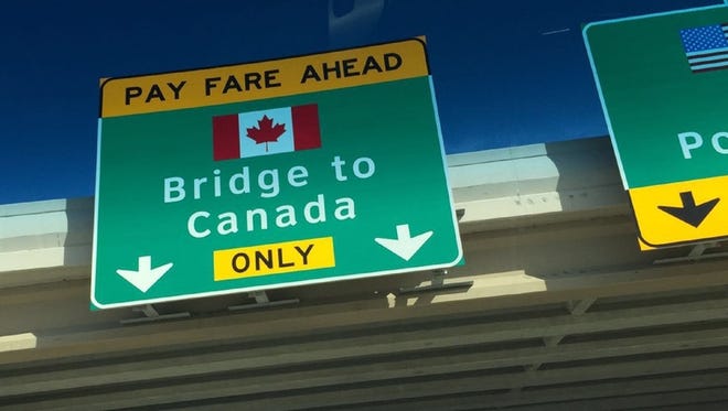 Sign posted on a freeway overpass pointing toward bridge to Canada.