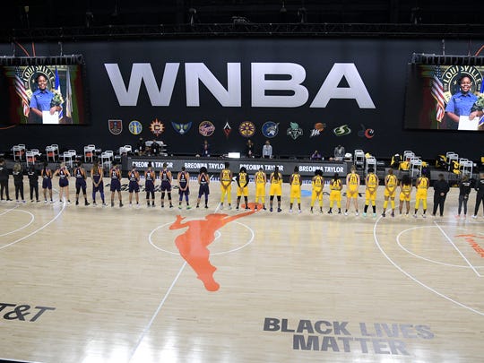 Members of the Phoenix Mercury, left, and Los Angeles Sparks stand for a moment of silence in honor of Breonna Taylor before a WNBA basketball game, Saturday, July 25, 2020, in Ellenton, Fla. (AP Photo/Phelan M. Ebenhack)