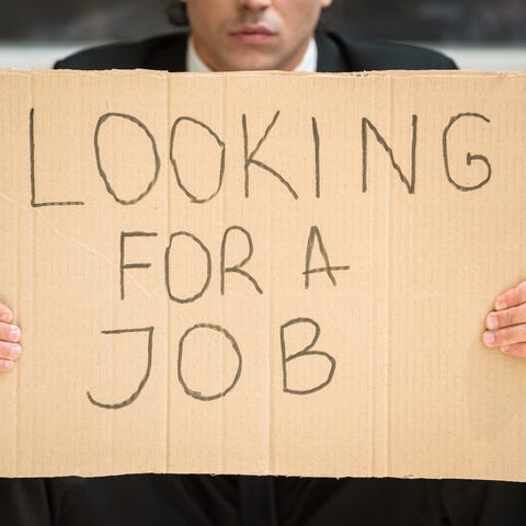 A businessman in a suit holding up a cardboard sig