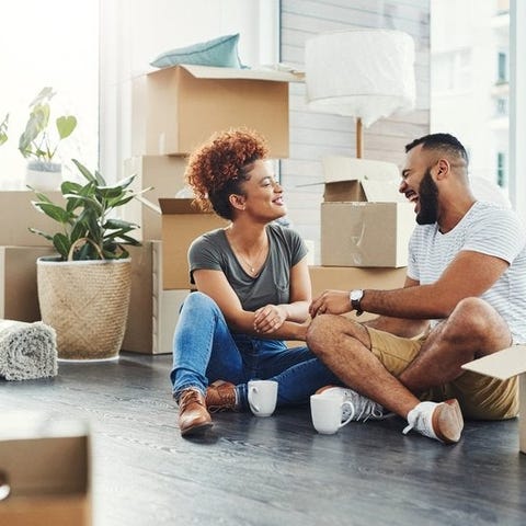 Two smiling people sitting on the floor between mo