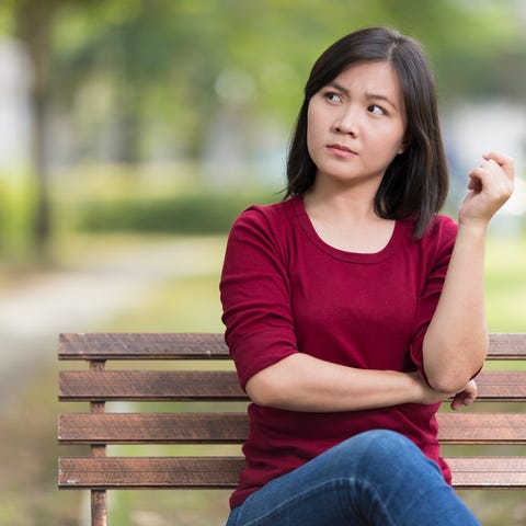 Woman looking askance while sitting on a park benc