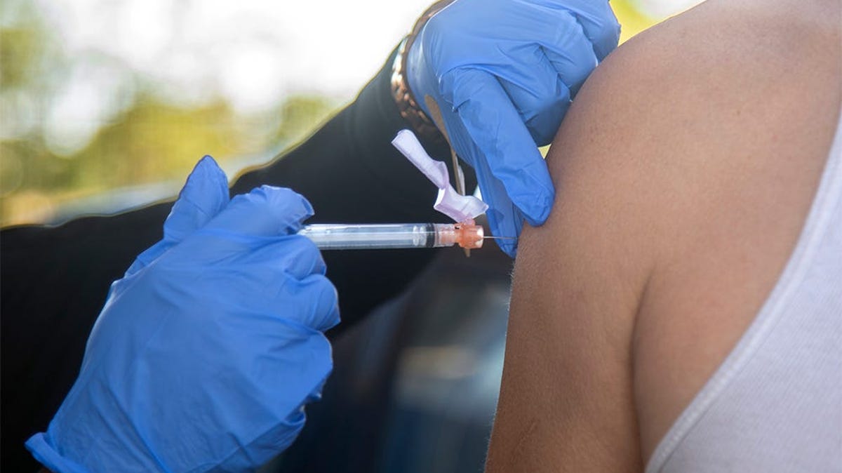 Nurse Lisedor Desrisiers with the San Joaquin County Clinics, left, gives a shot of the Johnson and Johnson COVID-19 vaccine to Edward Posada at an homeless encampment under the Interstate 5 bridge at Weber Avenue in downtown Stockton, California.