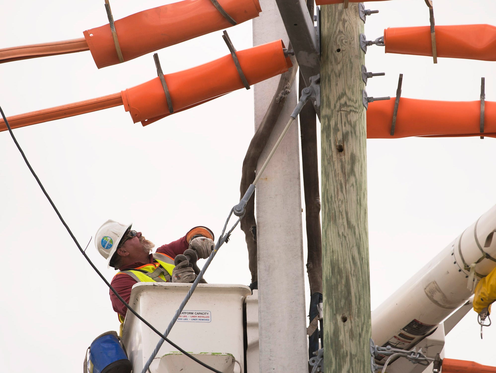 Florida Power & Light Co. line specialist Steve Bruno takes off the sling that secured the recently installed concrete utility pole to the crane as he and the FPL field crew install new utility poles designed to withstand winds of up to 145 mph, at 7