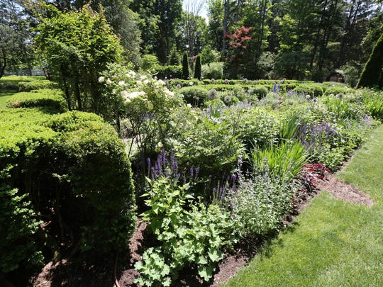 Old boxwood hedges line the edges of the perennial border.