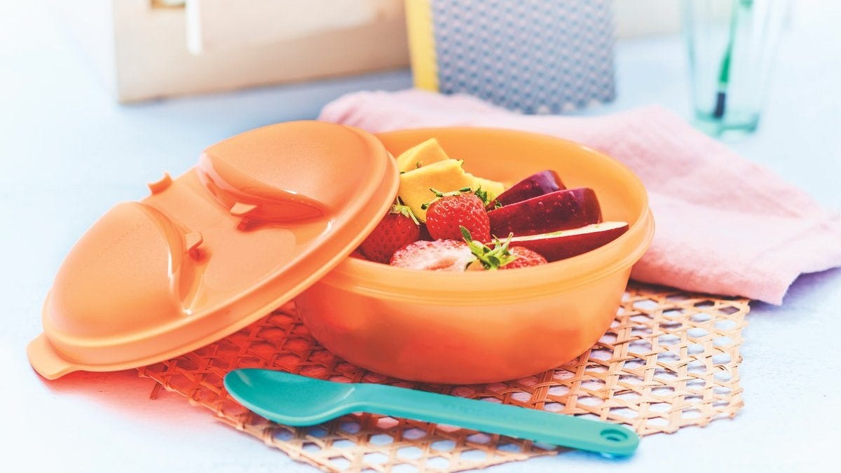 A plastic Tupperware container filled with fresh fruit