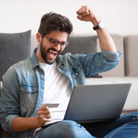 Man celebrating success while holding credit card.