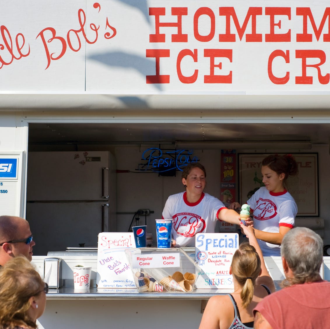 Amy Meyer and Chelsea Lolley, both of Eureka, serve ice cream to customers at Uncle Bob's Homemade Ice Cream stand on Friday afternoon at the Heart of Illinois Fair at Expo Gardens in Peoria.