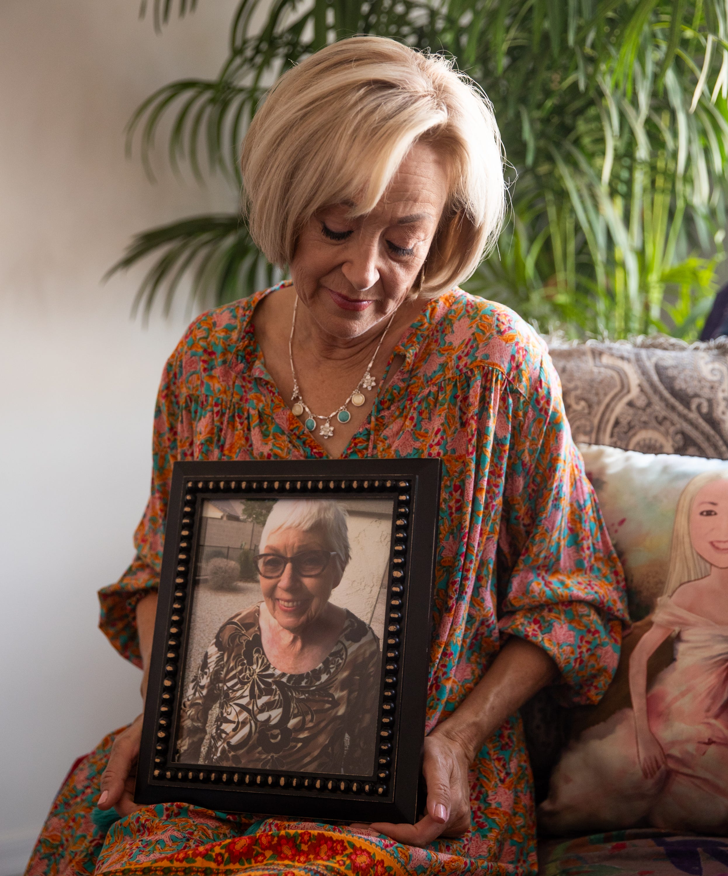 Michele Bixby poses for a portrait holding a framed photo of her mother, Anita Ferretti, inside her home in Eloy on Aug. 10, 2023.