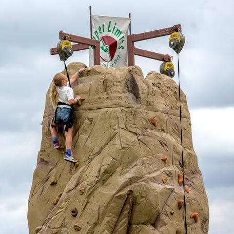 Andi Flessner, 7, of Peoria touches the top of the climbing wall during the Peoria Park District's Park-A-Palooza on Saturday, June 8, 2024 on the Peoria riverfront. The three-day festival featured a kids adventure area with bounce houses, a zip line, an obstacle course and other attractions, as well as live music, a soda pop tasting event, and a nighttime drone show.