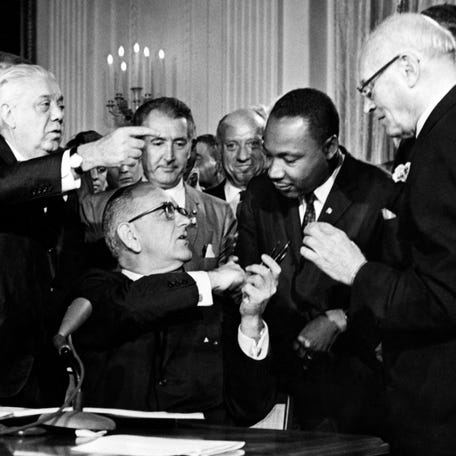 President Lyndon B. Johnson hands a pen to Rev. Martin Luther King after signing the historic Civil Rights Act in the East Room of the White House in Washington, D.C. on July 2, 1964.