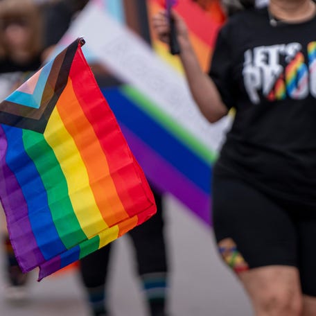 A parade attendee holds a progress pride flag, June 8, 2024, during the Indy Pride Parade on North Delaware Street in Indianapolis, Indiana.