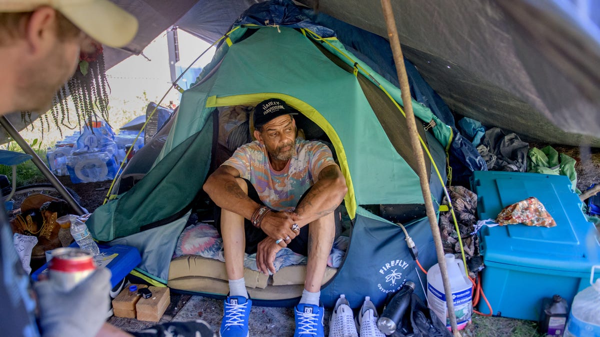 Glenn Giles, 59, hangs out in his tent under a tarp, chatting with visitors in an encampment along Interstate 74 behind the Peoria's Womens' Club and New Hope Apartments in downtown Peoria.