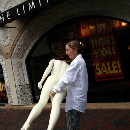 Marcie Ziv carries a Mannequin from The Limited store as it closes the location January 16, 2008 in Miami, Florida. Financial reports indicate that shoppers have tightened their belts on spending and manufacturers are seeing weak demand for cars and housing-related goods.