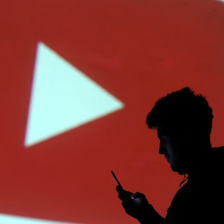 FILE PHOTO: A silhouette of a mobile user is seen next to a screen projection of Youtube logo in this picture illustration taken March 28, 2018. REUTERS/Dado Ruvic/Illustration/File Photo