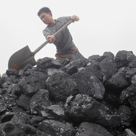 FILE PHOTO: A worker shovels coal as he loads a truck at a coal port in Hanoi February 23, 2012. REUTERS/Kham/File Photo
