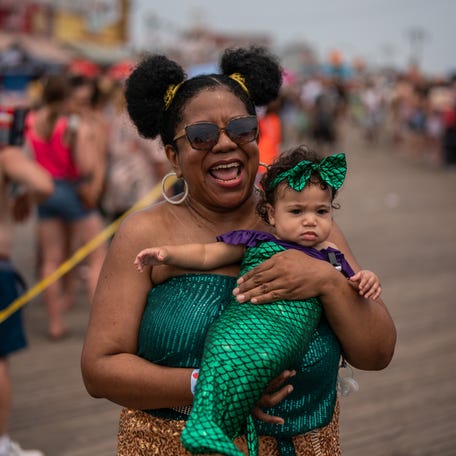 Yuli Franklin, with her daughter Olivia Coger, aged 7 months, walk the boardwalk during the annual Coney Island Mermaid Parade on June 22, 2024 in New York City.