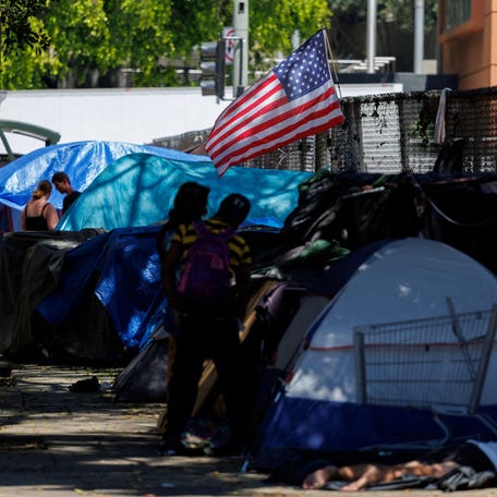 An American flag flutters over the tents of homeless people living along a sidewalk in Los Angeles, California, U.S., June 24, 2024. REUTERS/Mike Blake