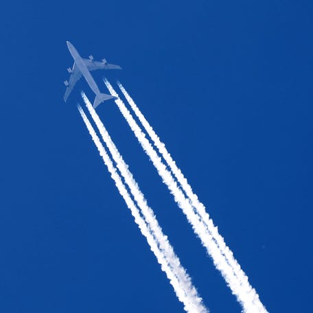 A plane leaves behind contrails as it flies in the sky over Paris, France, April 24, 2020. REUTERS/Charles Platiau