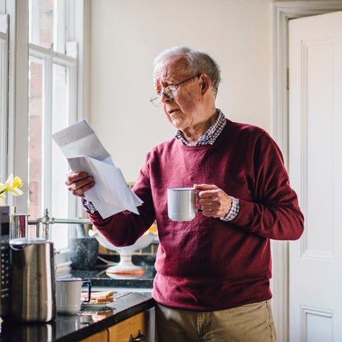 A man looks at a bill while drinking coffee.