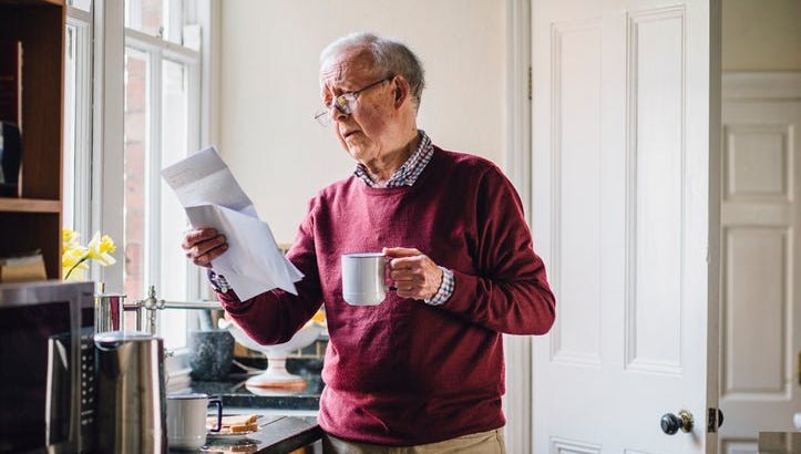 A man looks at a bill while drinking coffee.