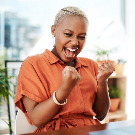 Person celebrating victory while looking at computer.