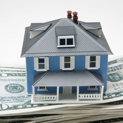 a small model house sitting on a stack of fifty do