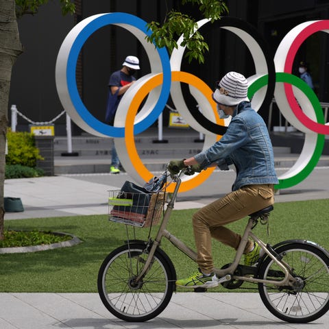 A woman rides a bicycle near the Olympic Rings Wed