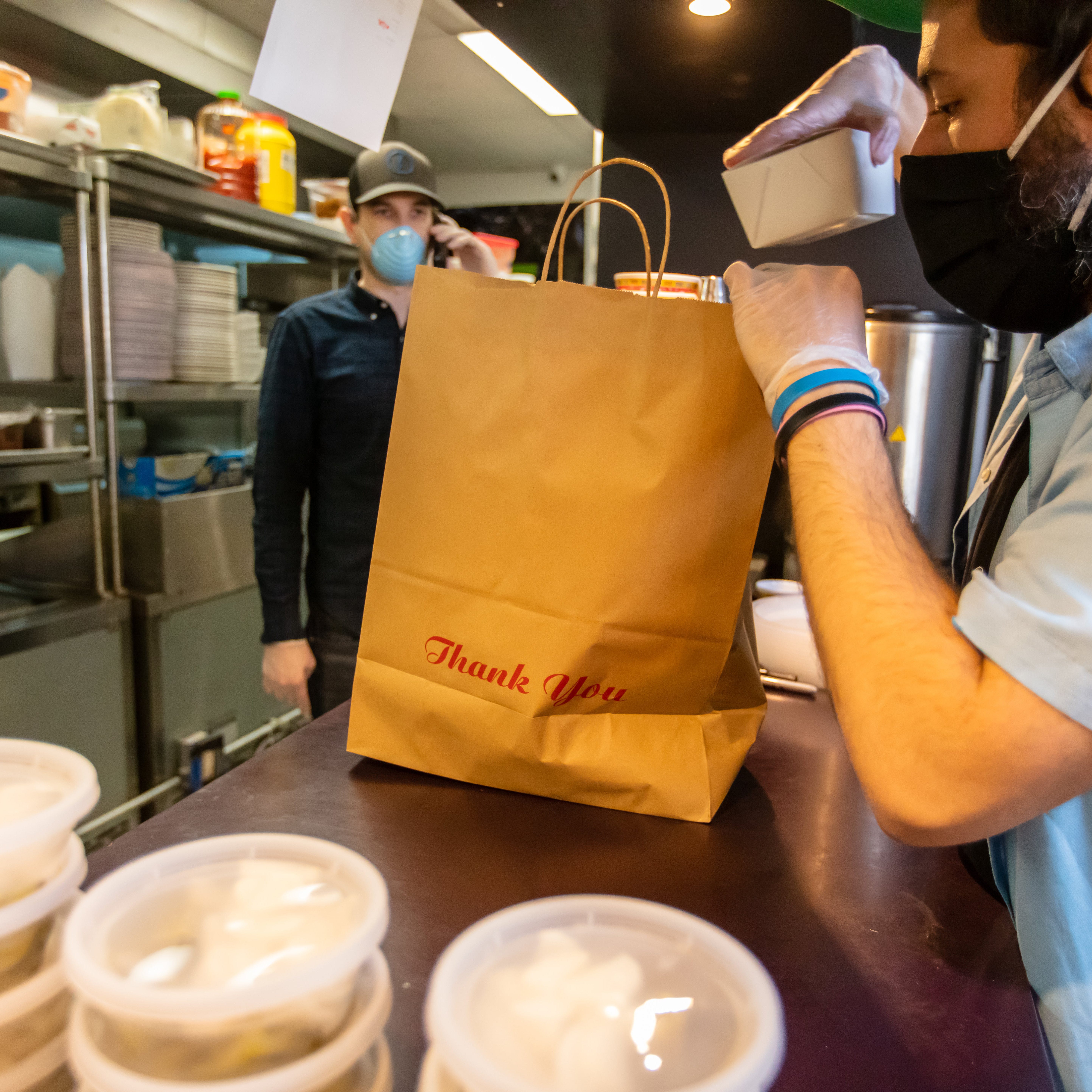 Restaurant worker preparing food for delivery driver.