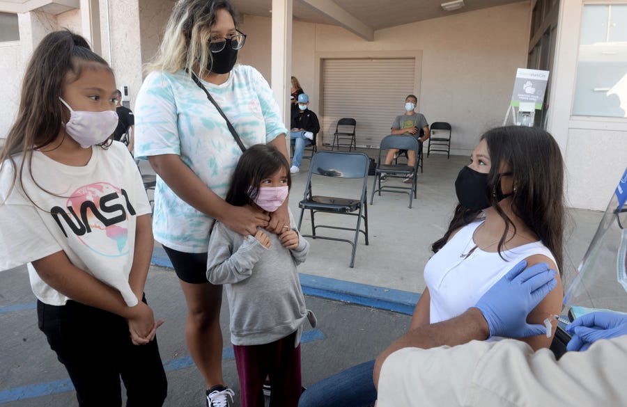 Left to right, Alana Alfaro, 9, and her mother Tracie Alfaro, holding Penelope Alfaro, 6, watch their sister Juliet Alfaro, 13, get vaccinated at the Rio Mesa High School pop-up vaccination clinic Sept. 2 in Oxnard, California. (Juan Carlo/Ventura County Star)