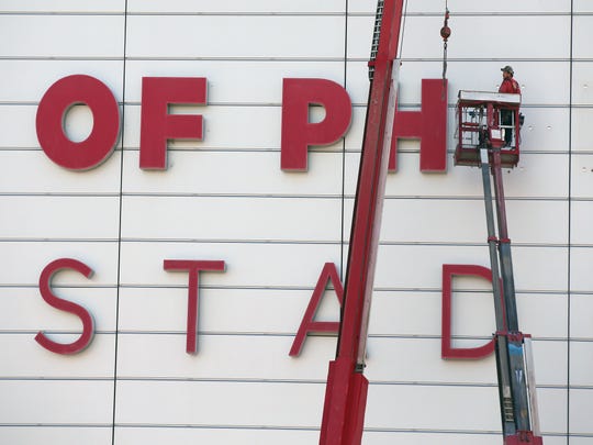 Workers remove the University of Phoenix Stadium signs on Sept. 4in Glendale, Ariz.