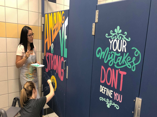 Teachers paint positive messages on bathroom stalls