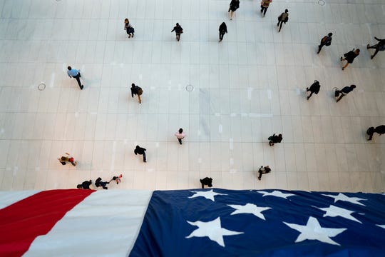 People walk under an American flag inside the Oculus, part of the World Trade Center transportation hub, on the anniversary of 9/11 terrorist attacks in New York on Tuesday, Sept. 11, 2018.