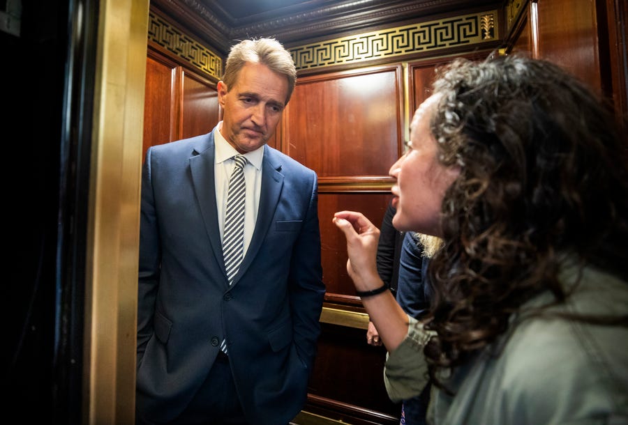 Ana Maria Archila, a survivor of a sexual assault, right, confronts Republican Senator from Arizona Jeff Flake in an elevator after Flake announced that he vote to confirm Supreme Court nominee Brett Kavanaugh in the Russell Senate Office Building in Washington, DC, on Friday.