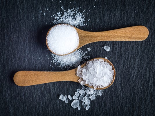 Different types of salt seen from above on two wooden spoons