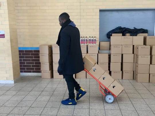 Devin Gardner, a former Michigan quarterback, helps with bottled water at Mumford High School.