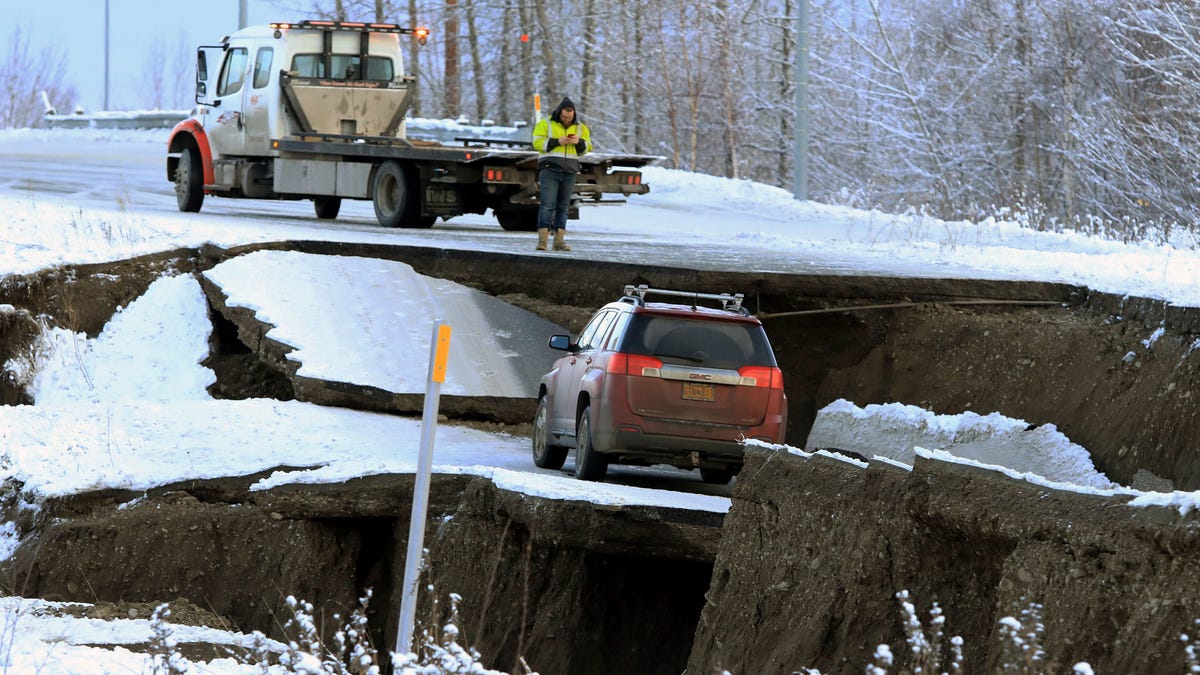 A tow truck driver assesses a car stuck on a section of an off-ramp that collapsed during an earthquake Friday morning, Nov. 30, 2018 in Anchorage, Alaska. The driver was not injured attempting to exit Minnesota Drive at International Airport Road. 