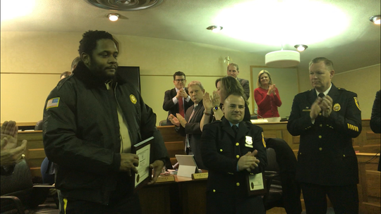 Keith Thornton, left, and Middletown Police Officer Nicholas Manochio, center, are applauded during Monday night's township committeeman for rescuing an elderly woman from a house fire on Saturday night.