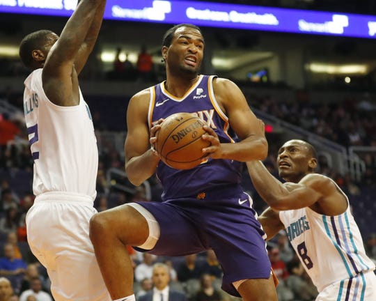 Phoenix Suns forward T.J. Warren (12) looks to pass between Charlotte Hornets forward Marvin Williams (2) and center Bismack Biyombo (8) during the first quarter in Phoenix January 6, 2019.