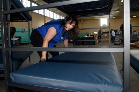 Francine Castanon places a mattress on a newly assembled bed at the west county regional homeless shelter in Oxnard. In 2019, the cannabis industry in Port Hueneme donated beds for the Oxnard shelter. The city of Oxnard is now in the process of permitting ten retail marijuana shops and drafting details of a problem that could allocate donations to homeless services.