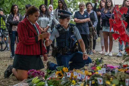 A police officer passes a candle to a schoolgirl during a students vigil near Al Noor mosque on March 18, 2019 in Christchurch, New Zealand.