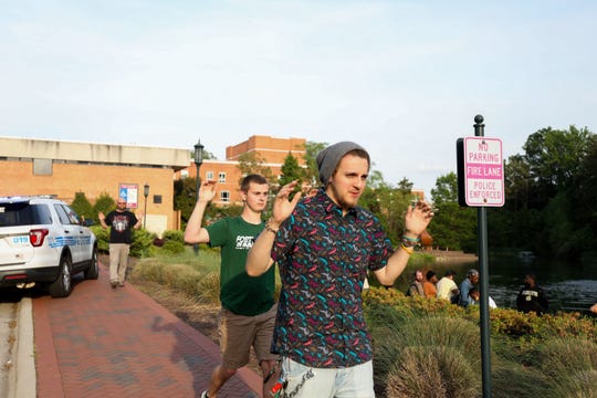 Students and faculty file out of buildings with their hands up during a lockdown after a shooting on the campus of University of North Carolina Charlotte in University City, Charlotte, on April 30, 2019. 