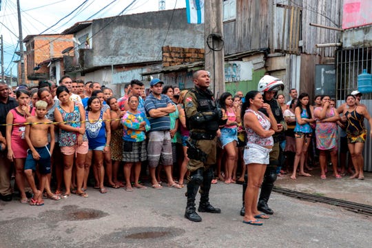 Residents gather outside a bar on Sunday after a shooting left at least 11 people dead in northern Brazil.